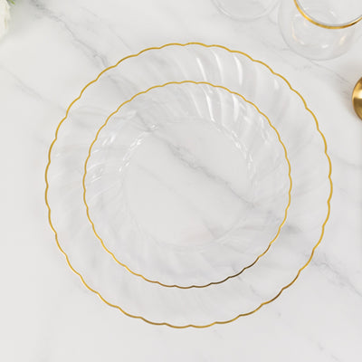 Clear plates with gold rim, stacked on a marble surface.
