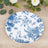 Blue floral decorative plate on a wooden surface with greenery.