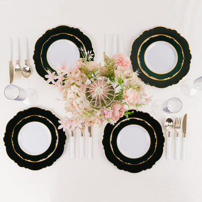 Elegant black and gold dinnerware set with floral centerpiece on a white table.
