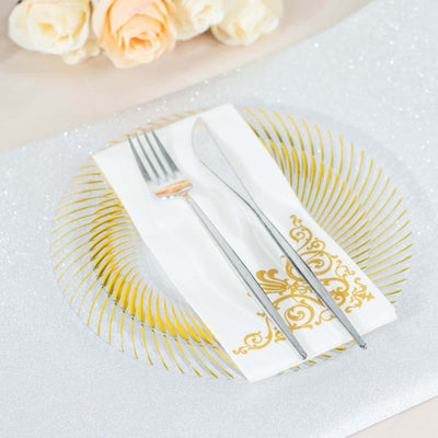 Elegant table setting with gold-accented plate, cutlery, and decorative napkin.