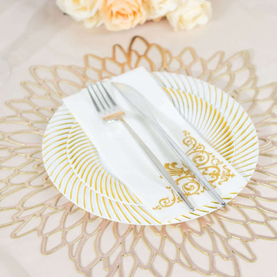Elegant gold and white dinner plate set with fork and knife on decorative table setting.