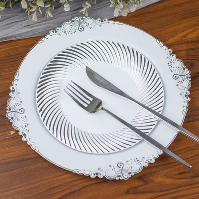 Elegant silver decorative plate with fork and knife on wooden table.