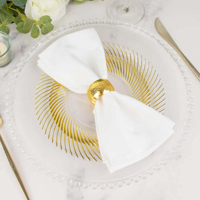 Elegant table setting with white napkin and gold napkin ring on clear plate.