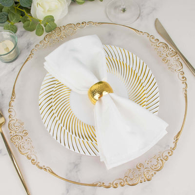 Elegant white napkin with gold ring on decorative plate, styled for dining.