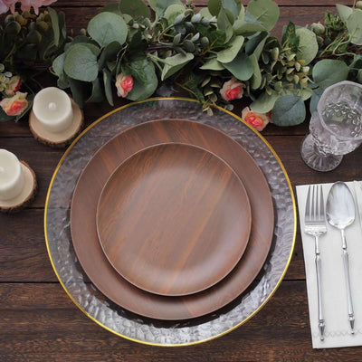 Elegant wooden dinner plates arranged on a rustic table with greenery and candles.