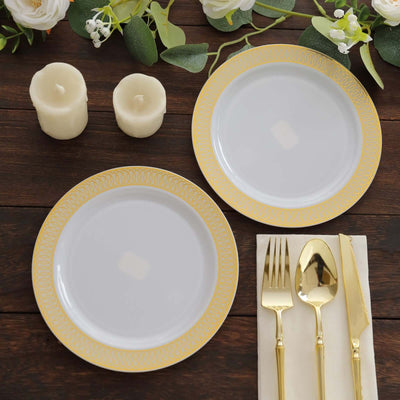 Elegant gold-trimmed dinner plates with cutlery and candles on a wooden table.