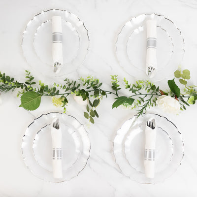 Elegant dinner setup with silver rimmed plates and napkin arrangements.