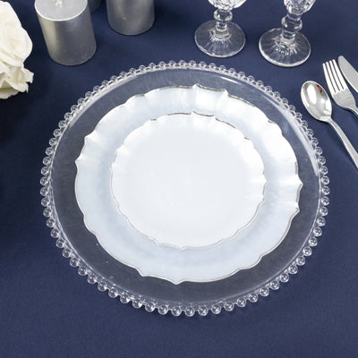Elegant clear charger plate with scalloped edges on a dark table setting.