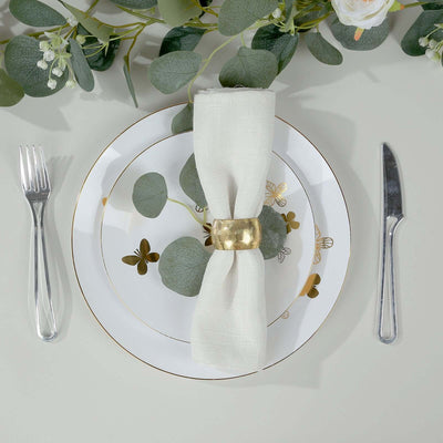 Elegant dining setup with white napkin and gold ring on decorative plate.