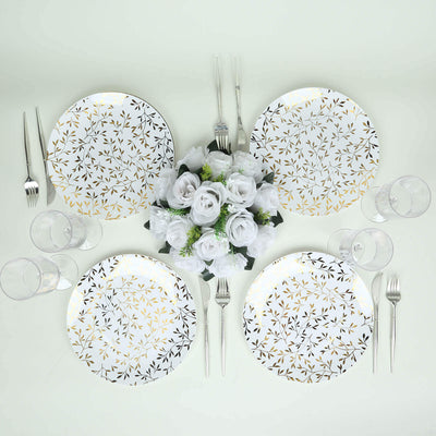 Elegant dinnerware set with gold leaf design and floral centerpiece.
