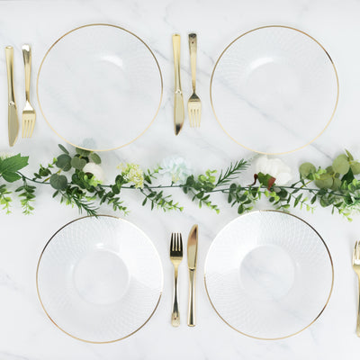 Elegant dinner setting with clear plates and gold utensils on a marble table.