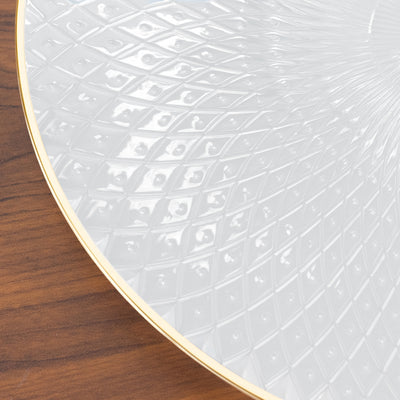 Decorative white plate with textured design and gold rim on wooden surface.