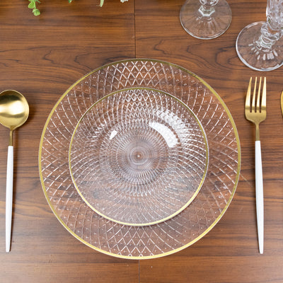 Elegant glass dinner plates with gold trim on a wooden table setting.