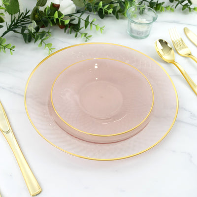 Elegant pink plates with gold trim stacked on a marble table setting.