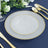 Elegant frosted glass plate with gold trim on a blue table setting.