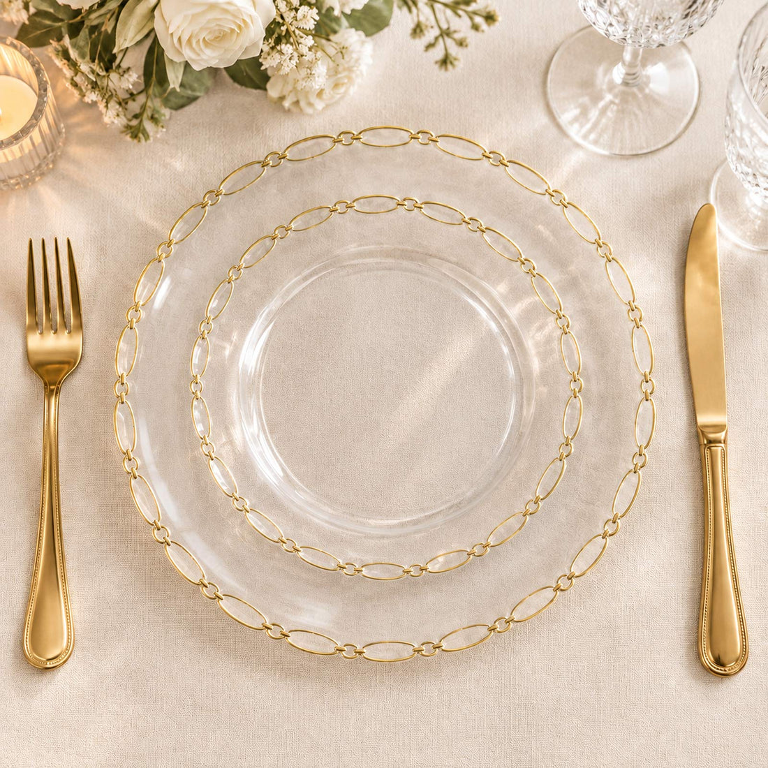 Elegant gold chain glass charger plate with gold flatware on a white table setting