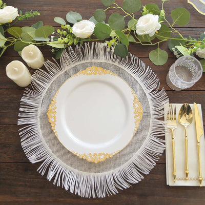 Elegant white plate with gold detailing on a fringed charger, surrounded by floral decor.