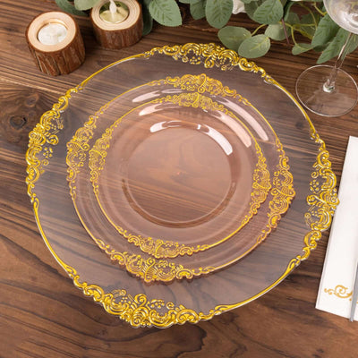 Elegant transparent plates with golden ornate design on wooden table.