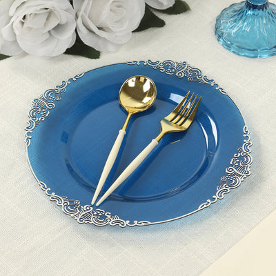Blue decorative plate with gold utensils on a textured tablecloth.