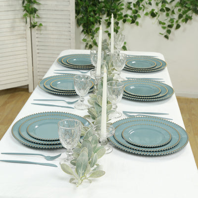 Elegant table setting with teal plates, crystal glassware, and candles.
