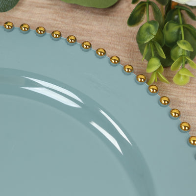 Teal plate with gold bead trim on a wooden surface.