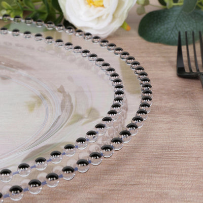 Clear glass plate with black beaded rim on wooden table.