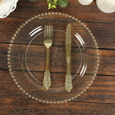 Elegant gold-rimmed clear plate with fork and knife on rustic wood table.