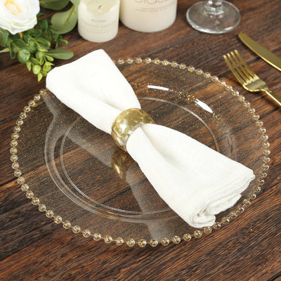 Elegant table setting with a glass plate, gold napkin ring, and white napkin.