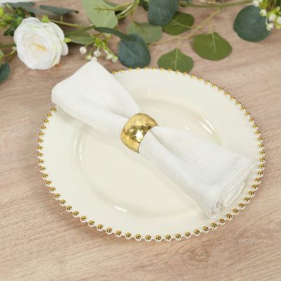 Elegant white napkin with gold ring on decorative plate.