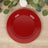Red decorative plate with gold beaded rim on a wooden surface.