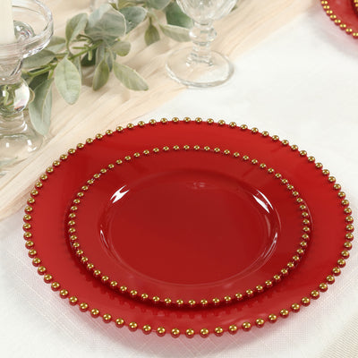 Red decorative plates with gold beaded edges arranged on a table.