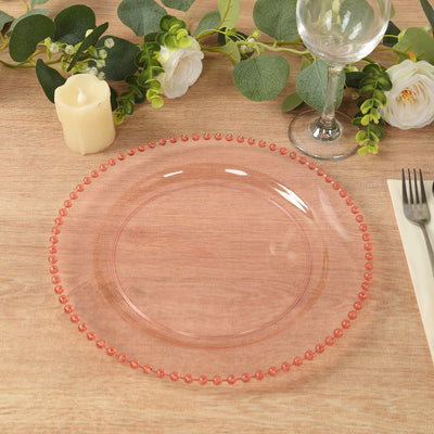 Pink decorative charger plate with beaded edge on a wooden table setting.