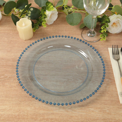 Clear glass plate with blue beaded rim on a wooden table setting.