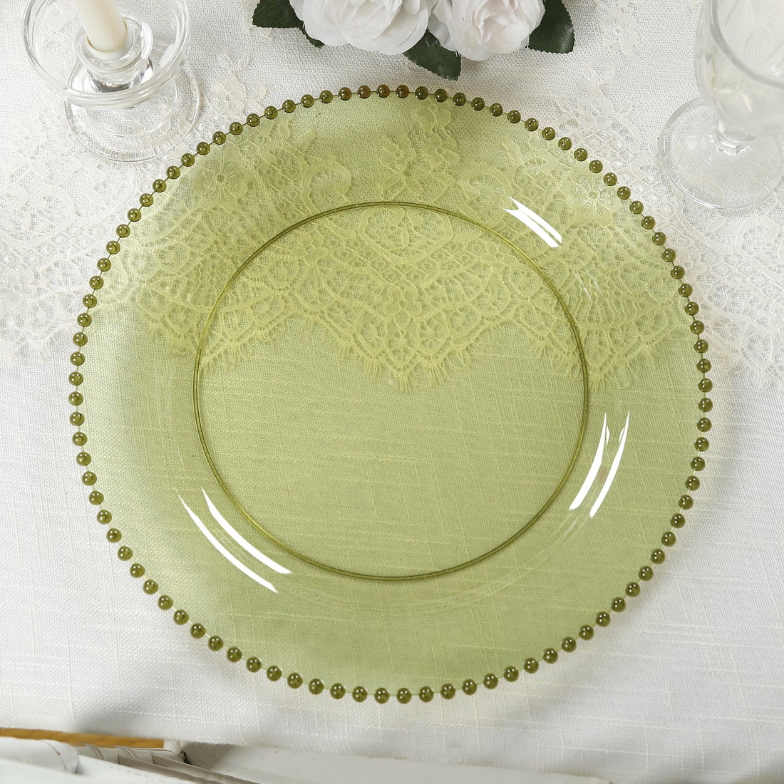 Green glass plate with decorative beaded rim on a textured tablecloth.