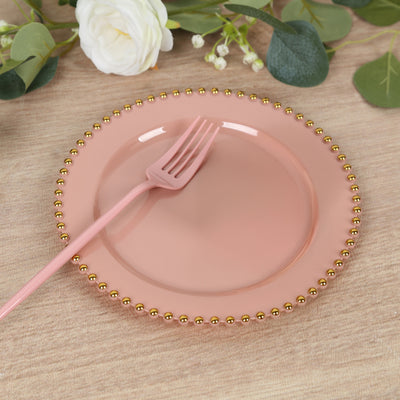 Pink decorative plate with gold bead trim and pink fork on a wooden surface.