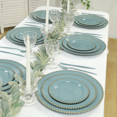 Elegant teal dinnerware set with gold beaded rims on a beautifully arranged table.