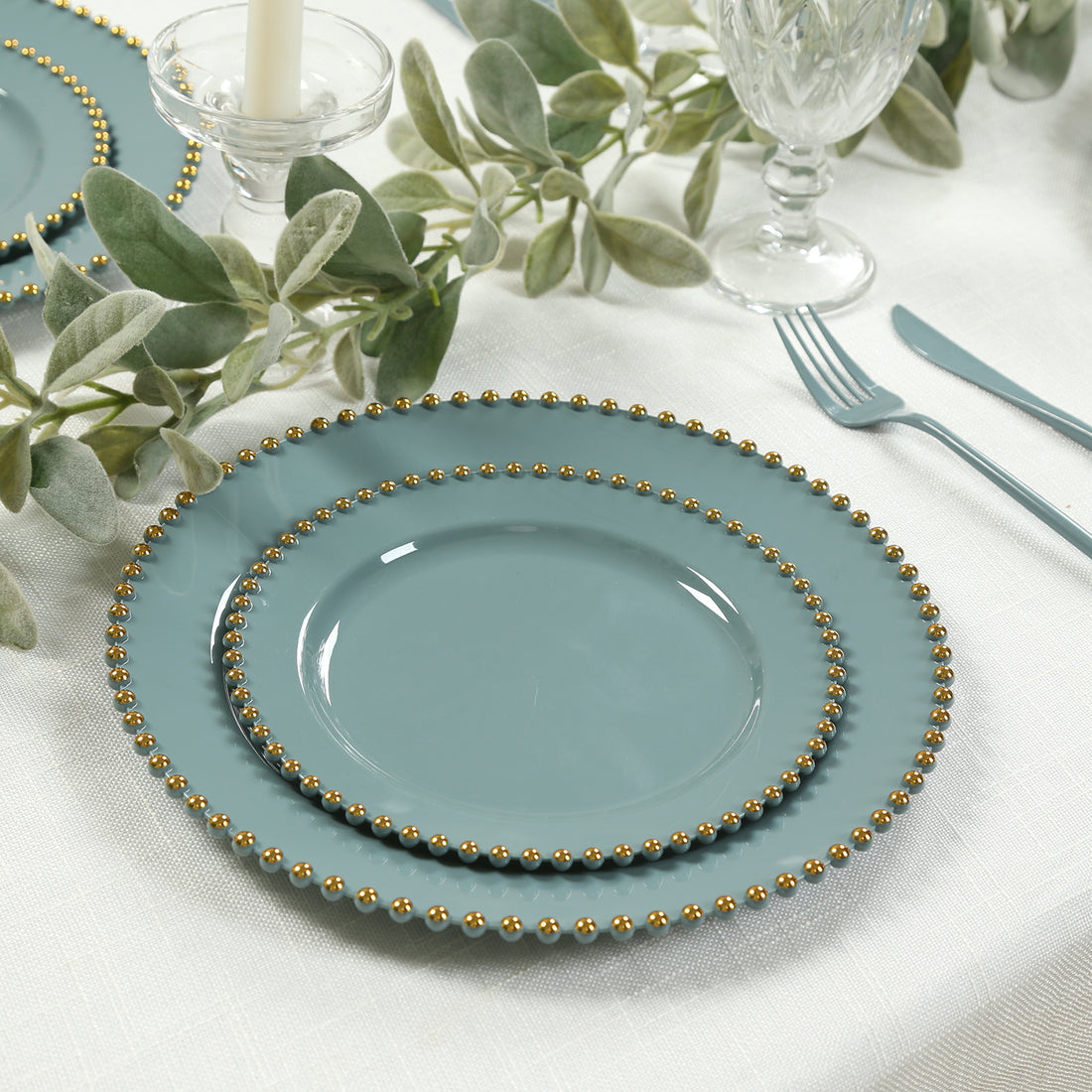 Elegant teal plates with gold bead accents, stacked on a table setting.