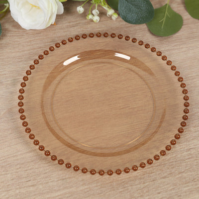 Clear decorative plate with brown beaded rim on a wooden surface.