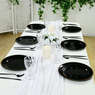 Elegant black dinner plates set on a styled table with floral decor and glassware.