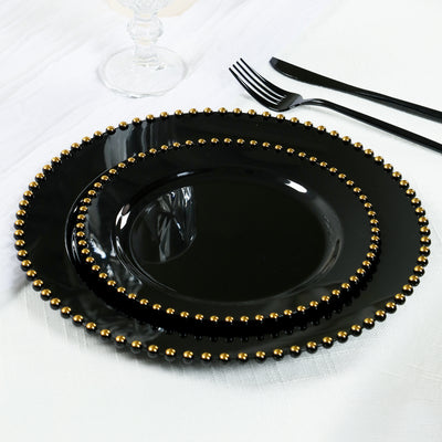 Black dinner plates with gold beaded trim, stacked elegantly on a table.