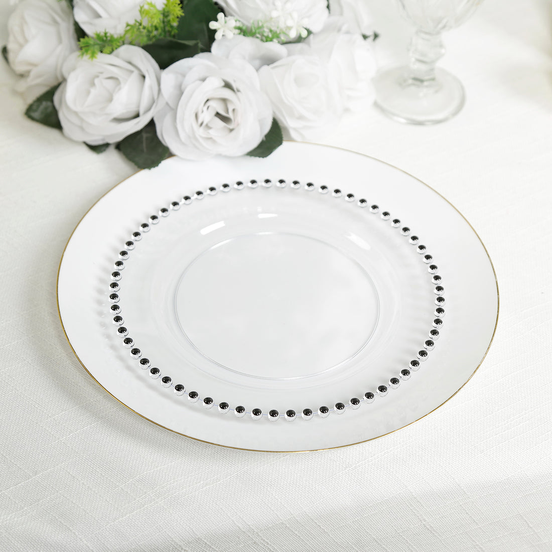 Elegant white plate with black beading and gold rim on a table setting.