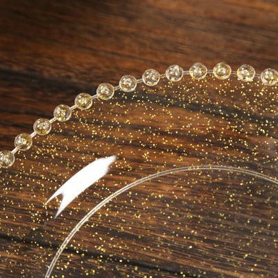 Clear glass plate with golden bead detailing and sparkling texture.