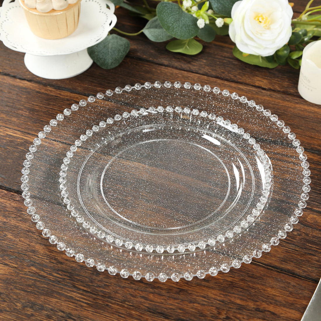 Clear decorative plates with beaded edges on a wooden table.