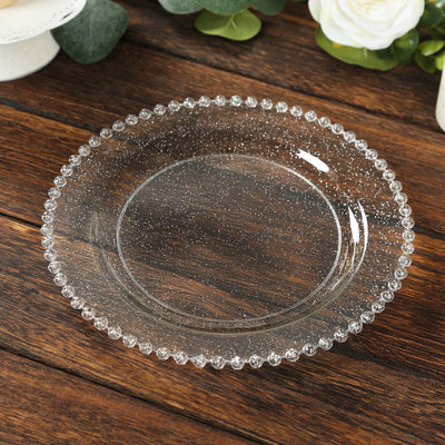 Clear glass plate with beaded rim on wooden table.