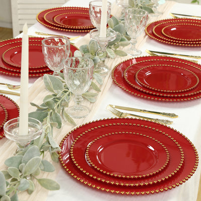 Elegant red dinner plates with gold beaded edges set for a festive table setting.
