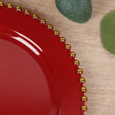 Red plate with gold beaded rim on textured surface