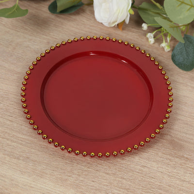 Red decorative plate with gold bead trim on a wooden surface.