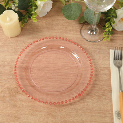 Pink decorative plate with bead-like edge on wooden table setting.