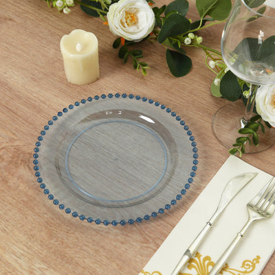 Clear plate with blue beaded rim on a wooden table setting.