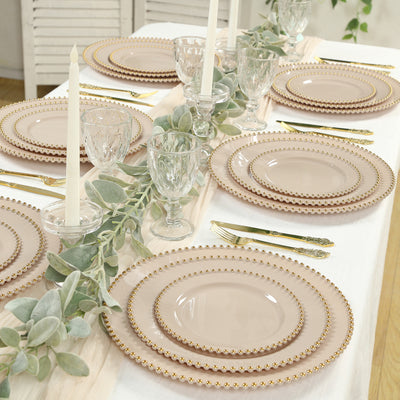 Elegant table setting with pink plates, crystal glasses, and greenery accents.